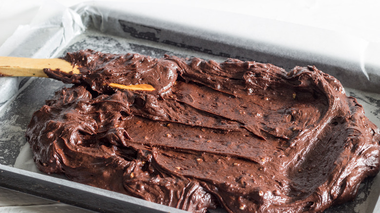 spreading brownie batter into a tray