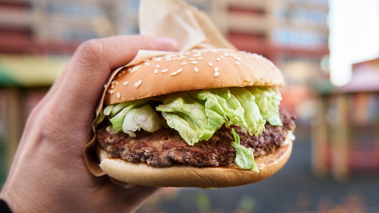 A hand holding a McDonald's hamburger