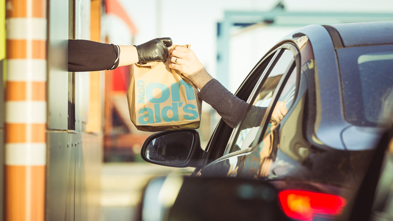 A person accepts a McDonald's take out bag from their car