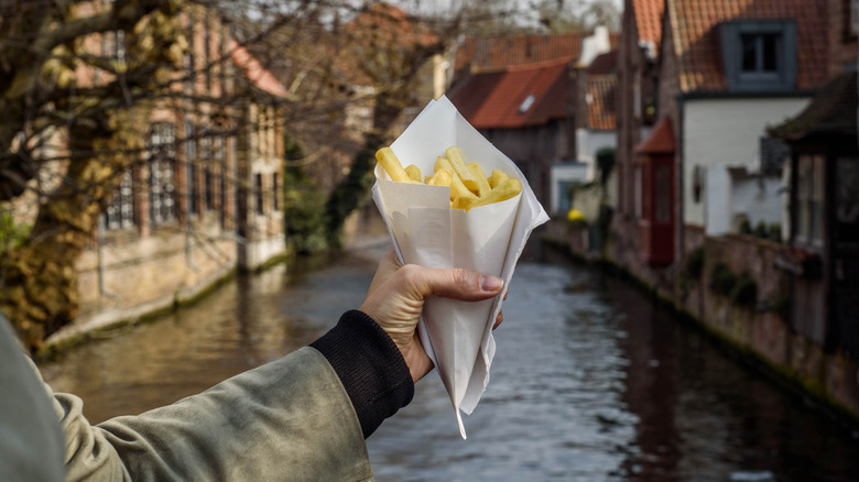 A woman holds a cone full of fries