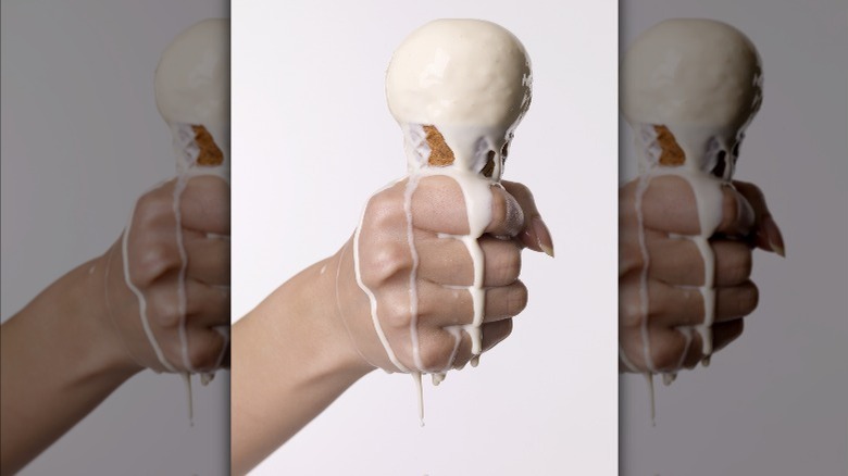 Person holding a melting ice cream cone