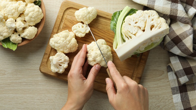 Person chopping cauliflower on cutting board