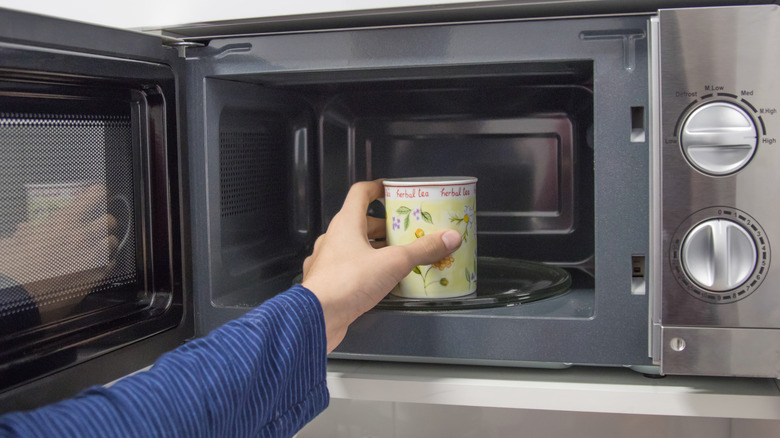 hand putting a mug in the microwave