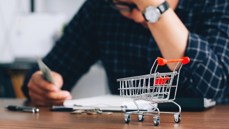 holding cash with grocery cart