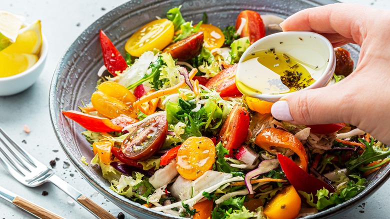 pouring dressing over a salad