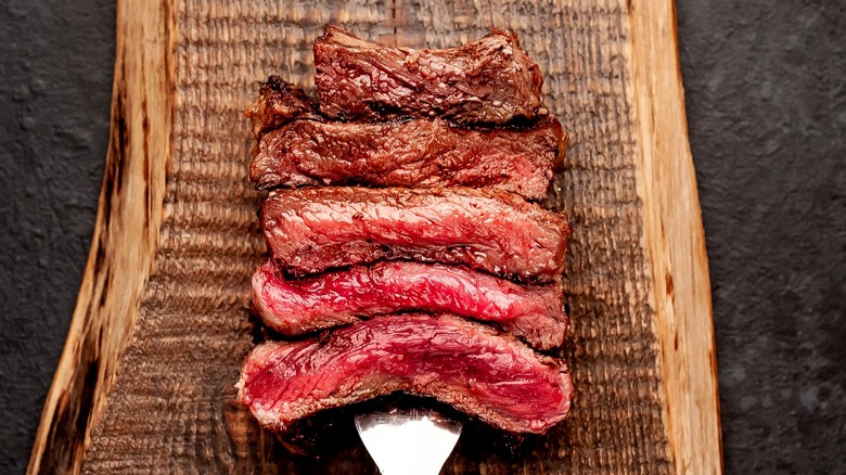 sliced steak on wooden board 