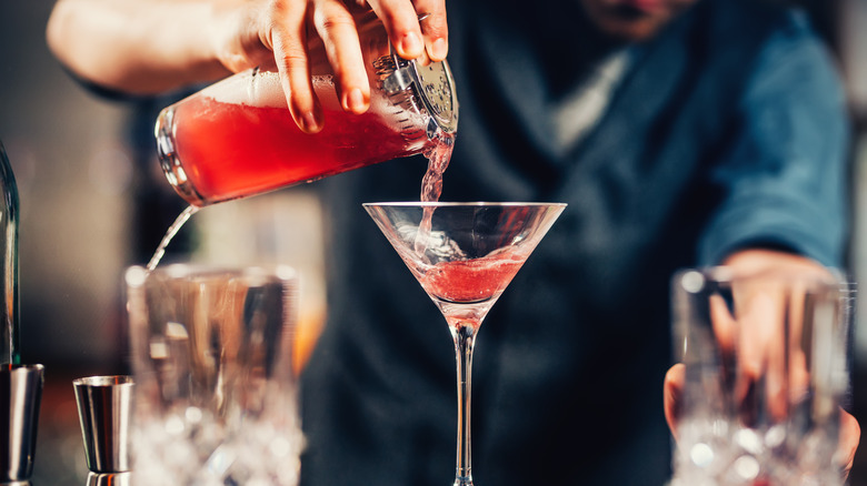 bartender straining cocktail into glass
