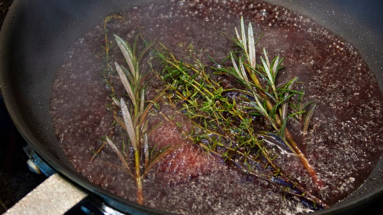 Deglazing a pan with liquid and herbs