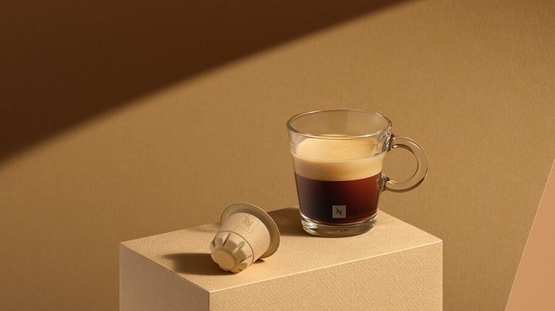 Nespresso compostable pod beside cup of coffee