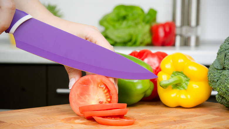 ceramic knife cutting a tomato on a wood board