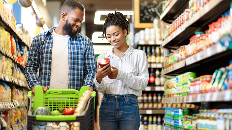 two shoppers filling a cart in a grocery store