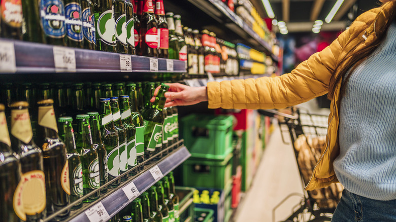 A person picks a bottle off of a shelf