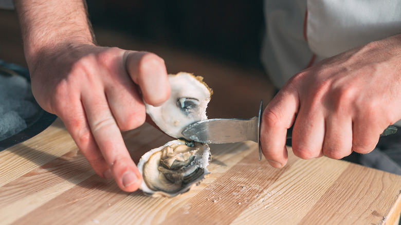 man shucking a raw oyster