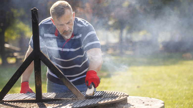 man cleaning outdoor grill with brush