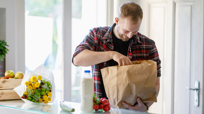 Man unpacking a paper grocery bag in the kitchen