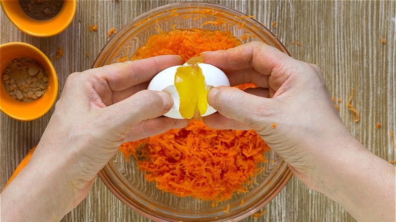cracking egg over shredded carrots