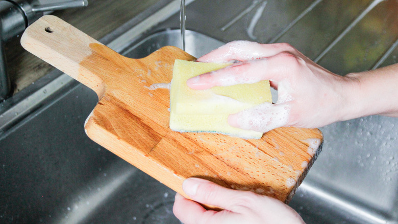 washing wooden board under faucet