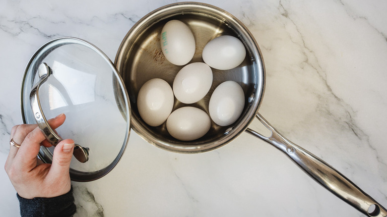 lifting the lid off eggs in saucepan