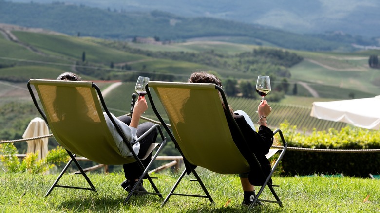 Two people in lounge chairs drinking wine at Riserva di Fizzano