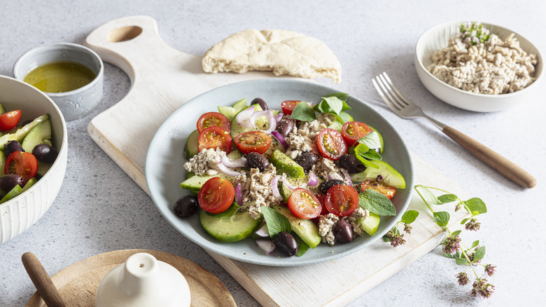 Greek salad in plate on cutting board