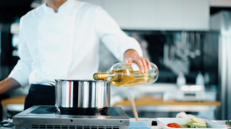 pouring white wine into pot