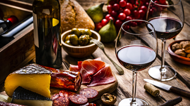 Red wine glasses with a charcuterie and cheese board.