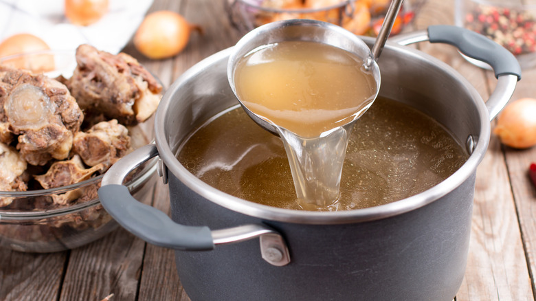 A pot of homemade beef bone stock with bones to the side