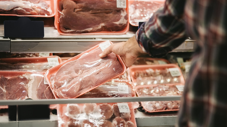 hand holding packaged grocery meat