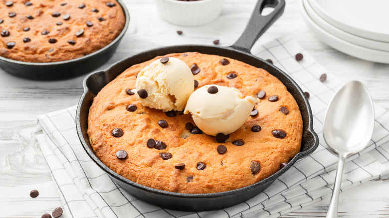 Cast iron skillet cookie with ice cream next to metal spoon