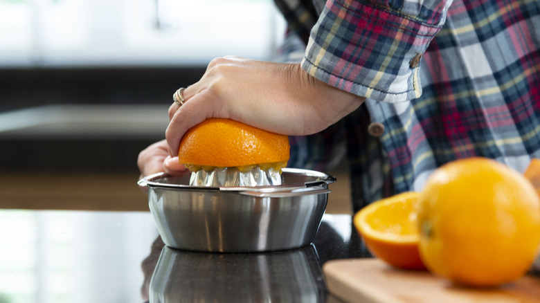 person juicing oranges in kitchen