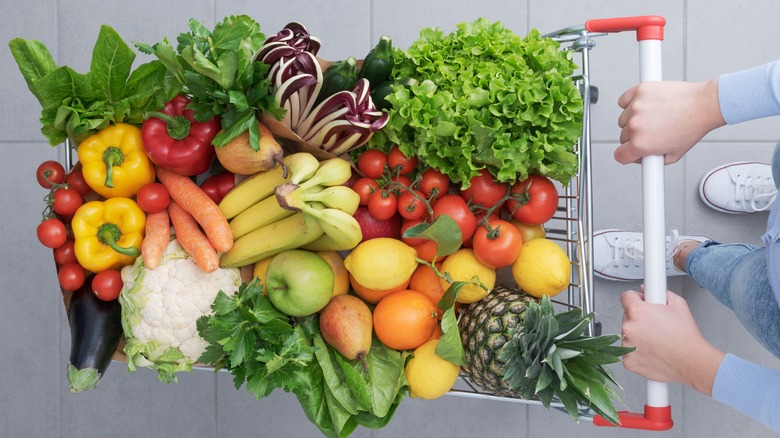 Hands pushing a cart full of produce