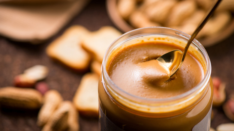 Spoon in open jar of peanut butter