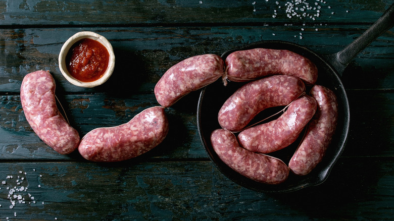 Links of raw sausages in a cast-iron pan