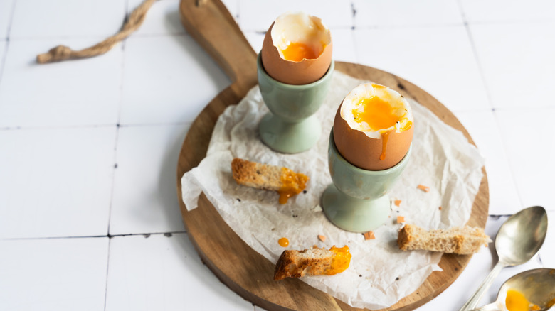 Two soft boiled eggs in egg cups with toast cut in thin wedges