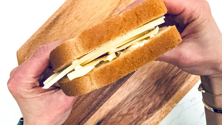 hands holding cheese sandwich