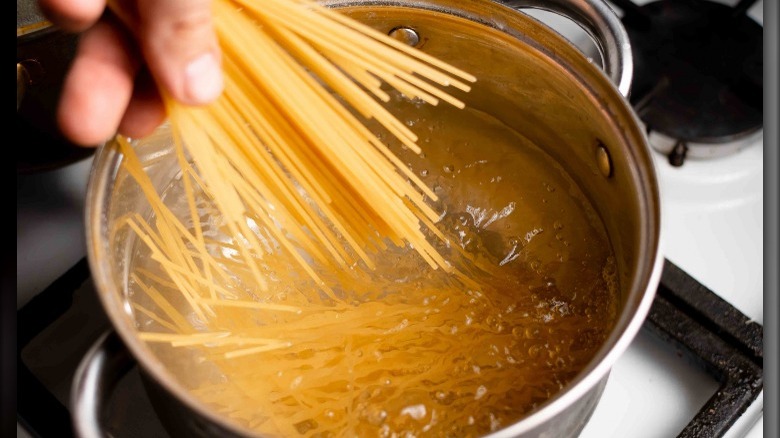 Adding spaghetti to pot of boiling water