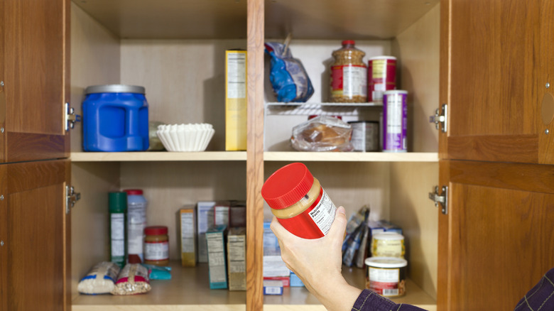 Woman storing peanut butter in the pantry