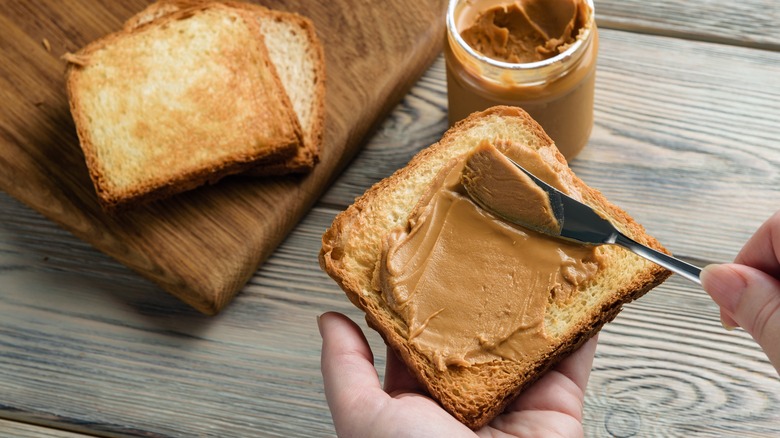 Woman spreading peanut butter on toast