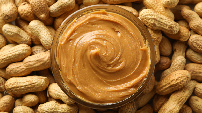 peanut butter in dish surrounded by peanuts