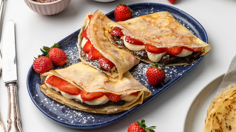 crepes with strawberries and cream on plate 