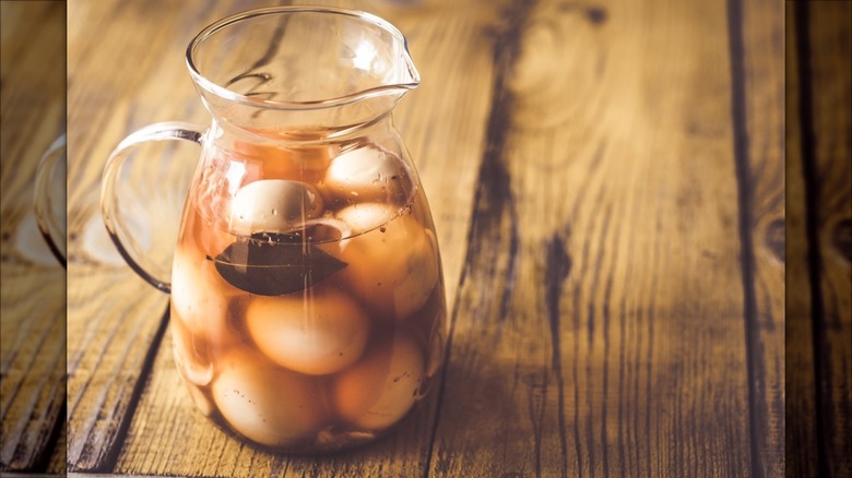 Jug of pickled eggs on wood table