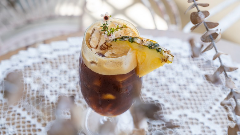 A glass of iced coffee garnished with pinneapple