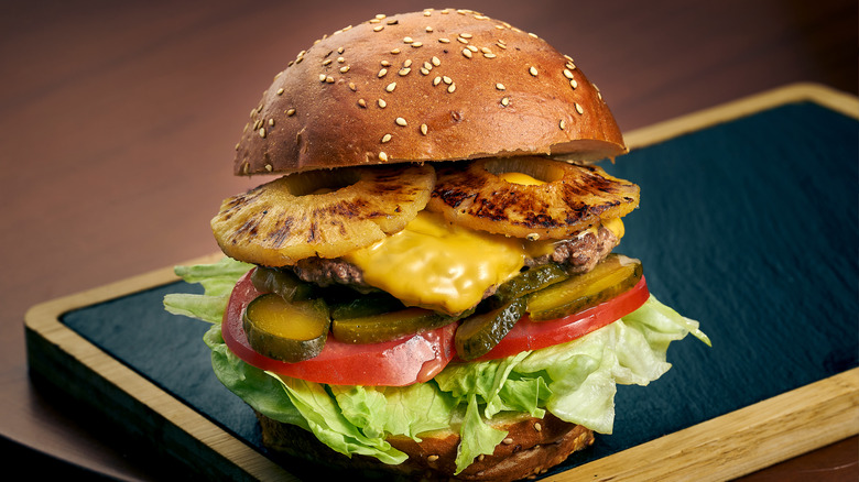 Cheeseburger with pineapple, pickles, and tomatoes