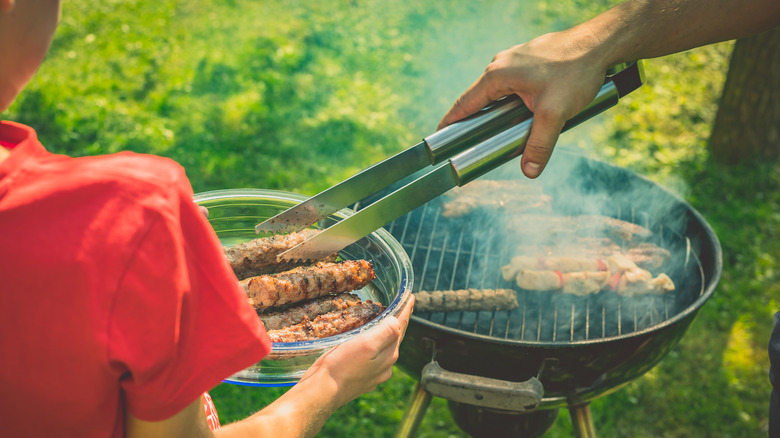 A man grills meats with his son