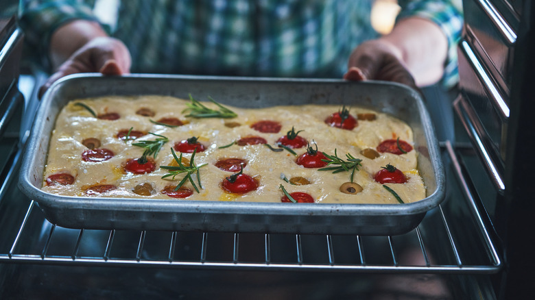 man putting focaccia into oven