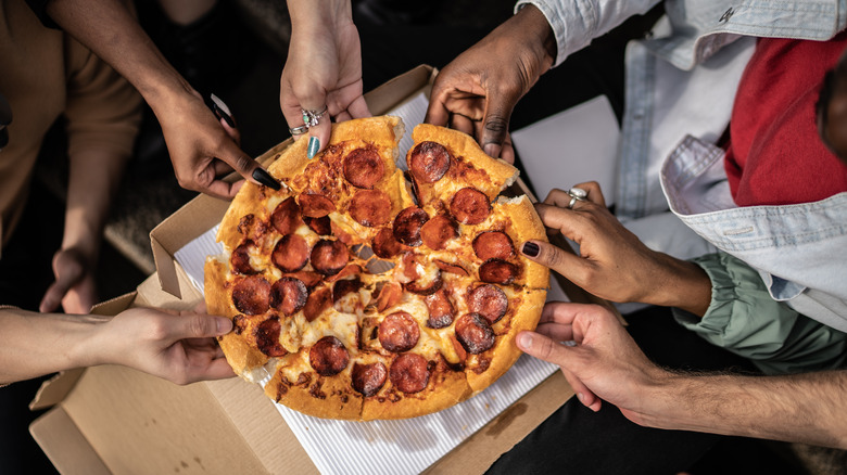 hands taking pizza slices