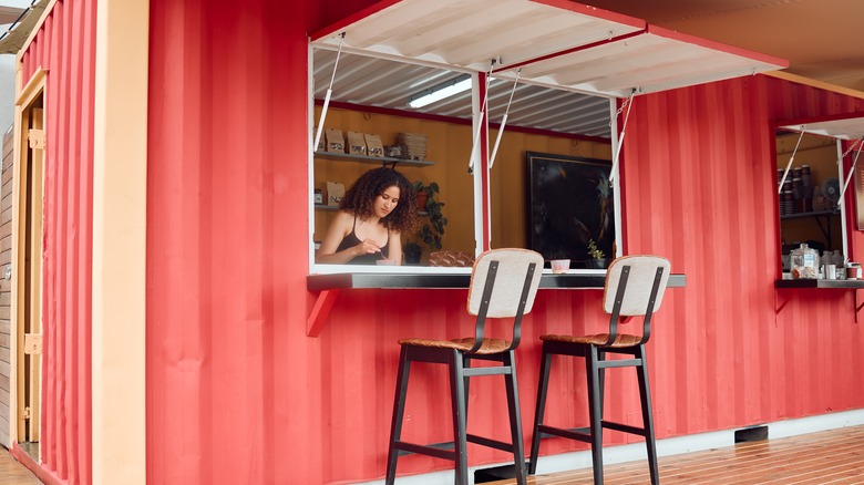 A woman sells coffee out of a converted shipping container