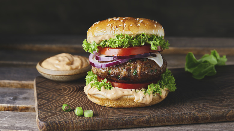 A hamburger with sauce on a serving board