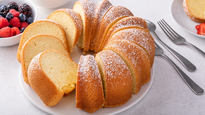 Bundt cake sliced on a plate with berries and powdered sugar