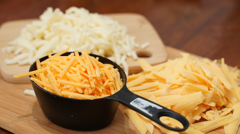 different types of grated cheese on cutting board